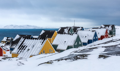 Yellow, blue, red and green inuit houses covered in snow at the fjord of Nuuk city, Greenland © vadim.nefedov