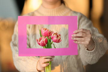 Young woman with bouquet of beautiful flowers and paper frame, closeup