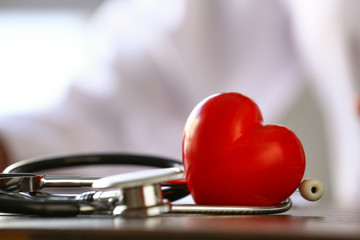 Heart with stethoscope on table of doctor, closeup
