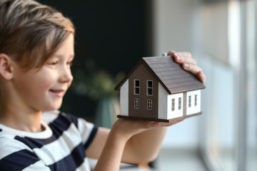 Little boy with model of house indoors. Concept of earthquake