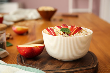 Bowl with tasty sweet oatmeal on wooden board