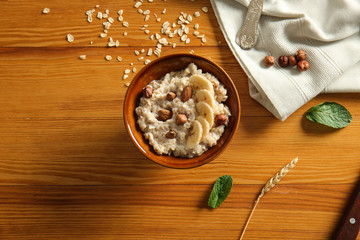 Obraz na płótnie Canvas Bowl with tasty sweet oatmeal on wooden table