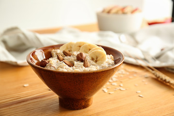 Bowl with tasty sweet oatmeal on wooden table