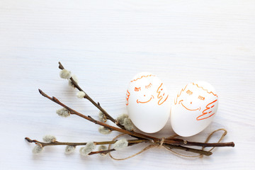 a pair of white eggs in the image of smiling sleeping chicks next to the willow twigs top view. happy together on holiday © zoomingfoto1712