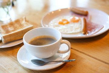Hot coffee and American breakfast with sunny side up eggs, bacon, toast