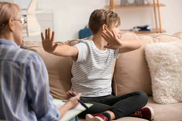 Female psychologist working with naughty little boy in office