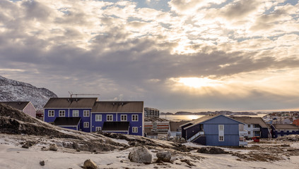 Fototapeta na wymiar Polar sunset over Inuit houses on the rocky hills with snow, Nuuk city, Greenland