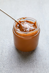 Jar of tasty salted caramel on grey background