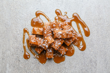 Tasty salty caramel candies on grey table