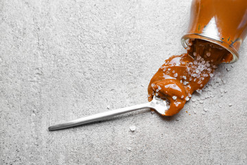 Jar of tasty salted caramel on grey background