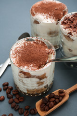 Glasses with tasty tiramisu on grey background