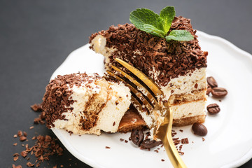 Plate with tasty tiramisu on dark background