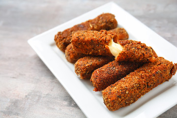 Plate with tasty mozzarella sticks on grey table
