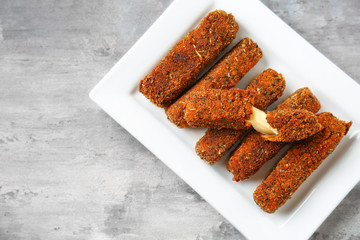 Plate with tasty mozzarella sticks on grey table