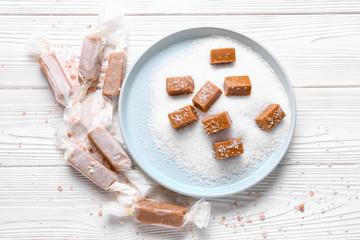 Plate with tasty salted candies on white table