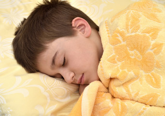 Cute young boy sleeping in bed. Close-up.