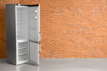 Open empty fridge near brick wall