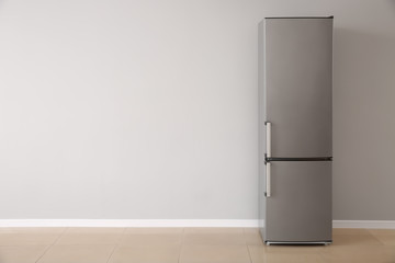 Modern fridge near white wall