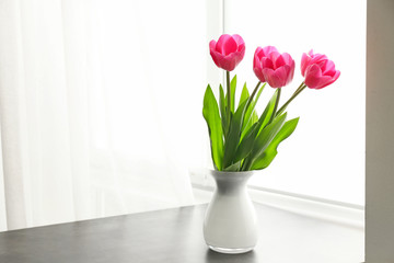 Vase with beautiful tulip flowers on table near window