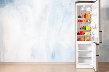 Open fridge full of food near color wall