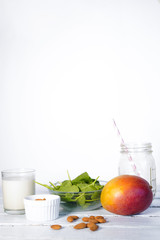 Components of healthy Green Reach Vitamins Smoothie with baby leaf spinach, mango, almond milk and strawberry