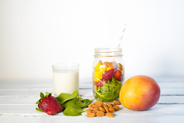 Components of healthy Green Reach Vitamins Smoothie with baby leaf spinach, mango, almond milk and strawberry