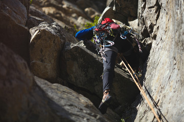 Climber overcomes rocky shelf on the background of a rocky relief closeup.