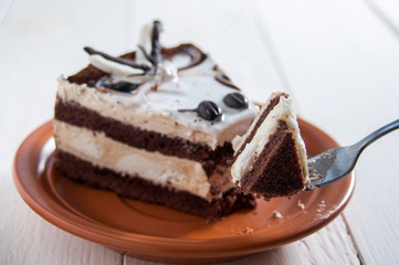 Delicious cake. Layers of delicate cream and chocolate sponge cake. On a plate, on dark wooden background. Dessert for the holiday. Eating.