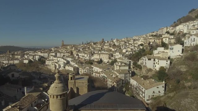 Drone shot revealing from behind of remaining wall of Renaissance catholic church Santa Maria, revealing white houses in Cazorla, Jaen, Andalusia, Spain