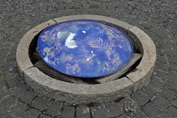 Old stone sewer well filled with garbage and with a blue cap