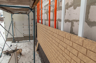 Fototapeta na wymiar Installing brick siding on the wall of the house