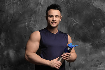 Sporty man with protein shake on grunge background