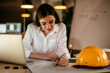 Young woman architect working on a project. Female engineer at her desk.