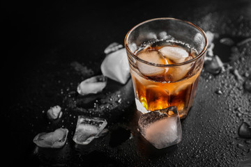 Glass of cold whiskey on dark background