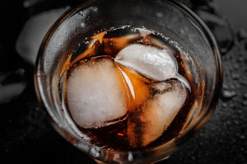 Glass of cold whiskey on dark background, closeup
