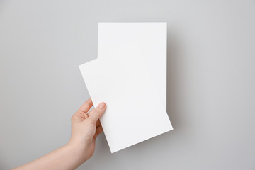 Female hand with blank invitation cards on light background