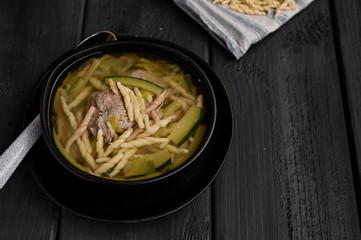 Dark photo of homemade pasta Trofie from Liguria . Italian healthy food concept with copy space. Soup with homemade pasta and meat.