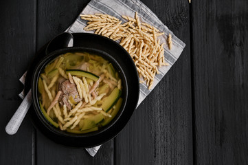 Dark photo of homemade pasta Trofie from Liguria . Italian healthy food concept with copy space. Soup with homemade pasta and meat.
