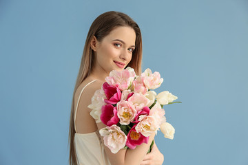 Young woman with bouquet of beautiful tulips on color background