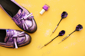 Stylish female shoes from iridescent material, darts and nail polish on color background