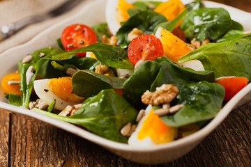 Delicious salad of fresh spinach, boiled egg, tomatoes, nuts and sunflower seeds