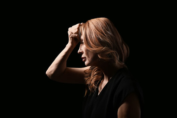 Obraz premium Mature woman suffering from headache on dark background