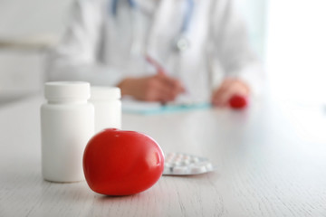 Red heart and medicines on table in clinic. Cardiology concept
