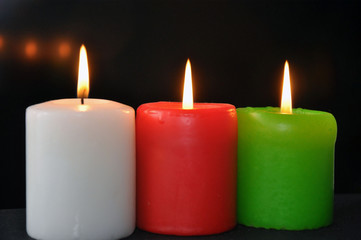 colorful burning candles set on black background.