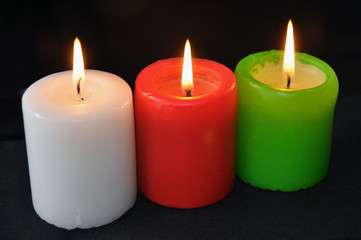 Obraz na płótnie Canvas colorful burning candles set on black background.