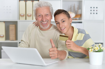 boy and grandfather with a laptop and credit card