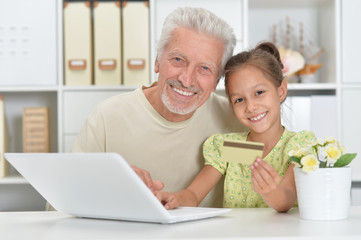Portrait of a grandfather and granddaughter using laptop together