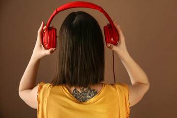 Young woman listening to music on color background