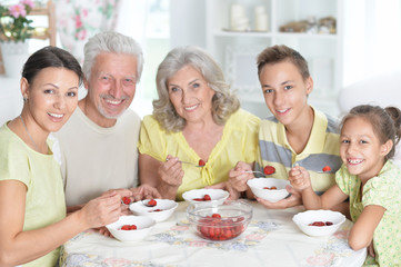 Portrait of big happy family eating fresh strawberries
