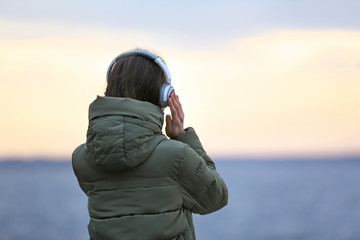 Fototapeta premium Young woman listening to music near river